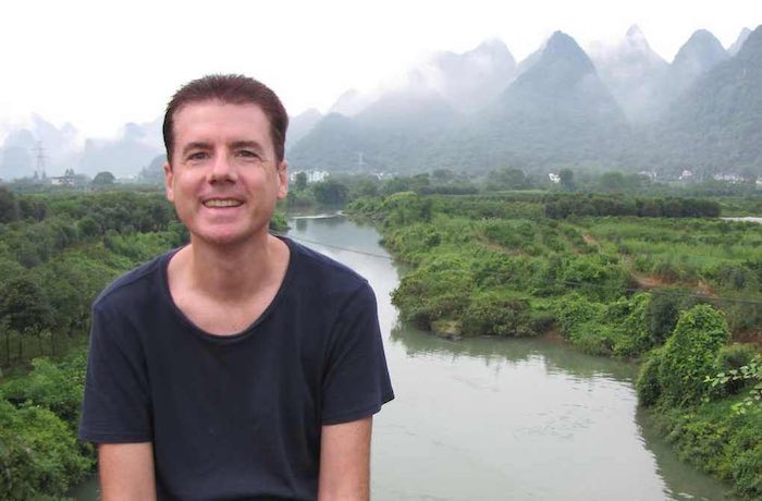 John Hunter with river and cloudy hills in the background