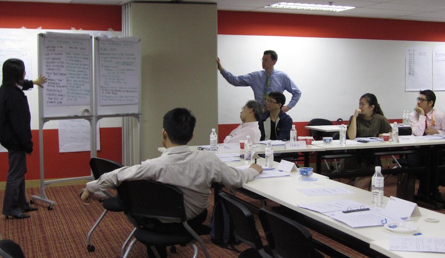 people at seminar listening to speaker at a flipchart